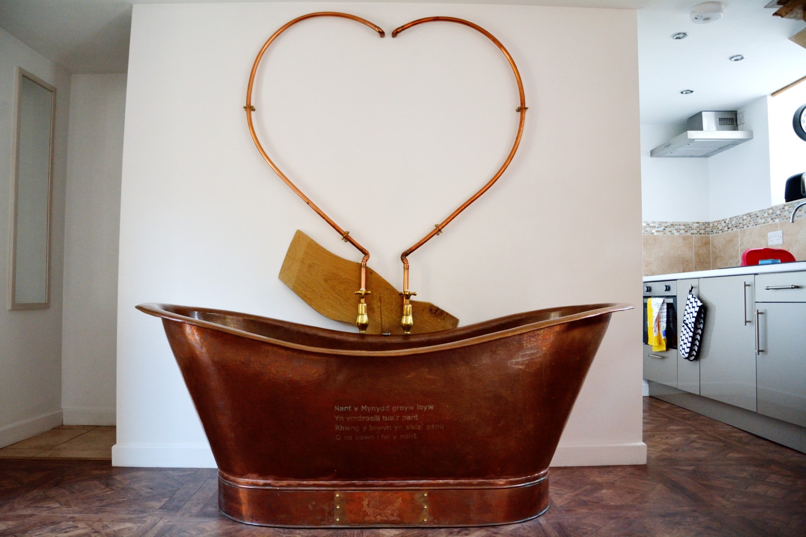 Experience a touch of luxury with a copper bathtub featuring a heart-shaped plumbing fixture, perfect for enhancing your UK winter break. Unwind in this modern bathroom oasis, reminiscent of retreats with private hot tubs.