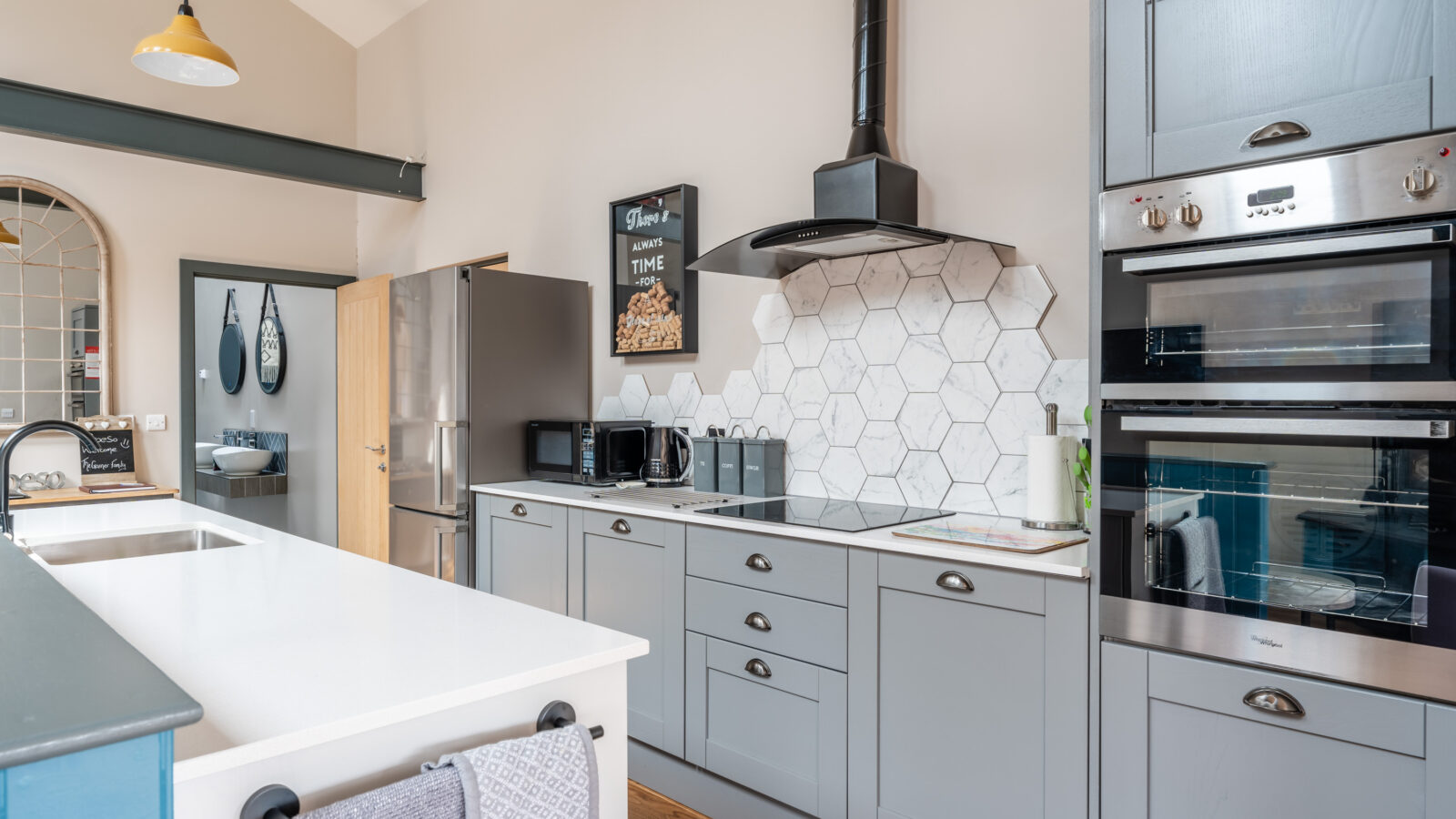 Modern kitchen with Stabl Nantcoy gray cabinets, a white island, double ovens, and a hexagonal backsplash.