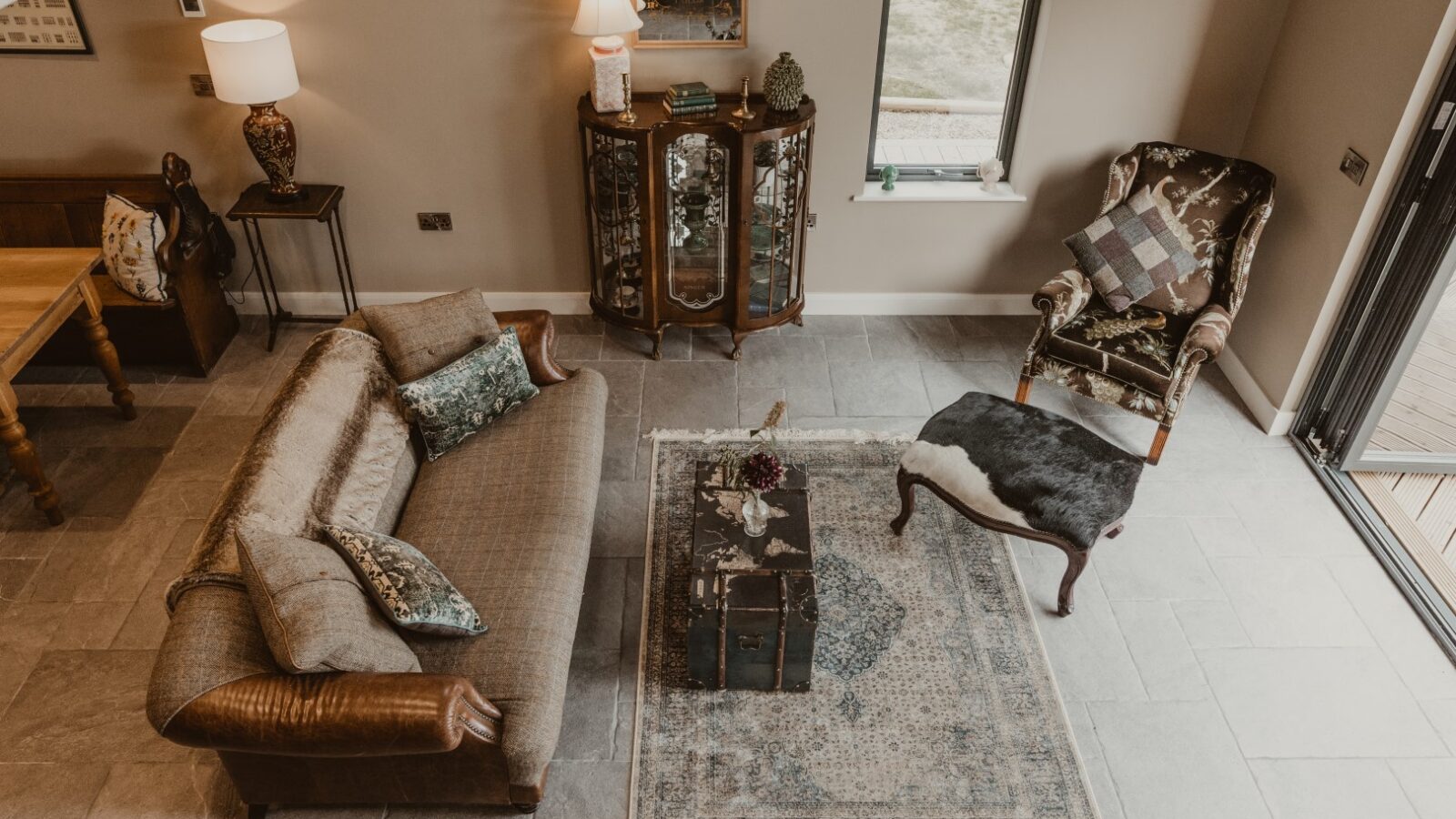 Overhead view of a cozy living room in a charming boat house, featuring a sofa, armchair, coffee table, decorative cabinet, and lamps.