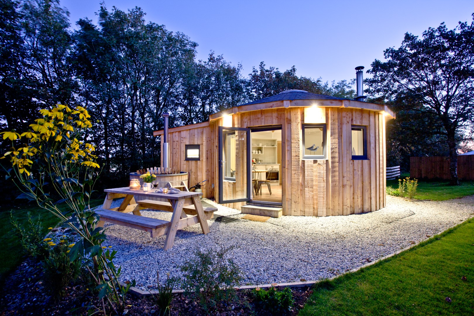 East Thorne Roundhouses pictured at night with warm cosy lighting and a hot tub all under a starry night sky. The most idyllic setting for winter weekend breaks in the UK