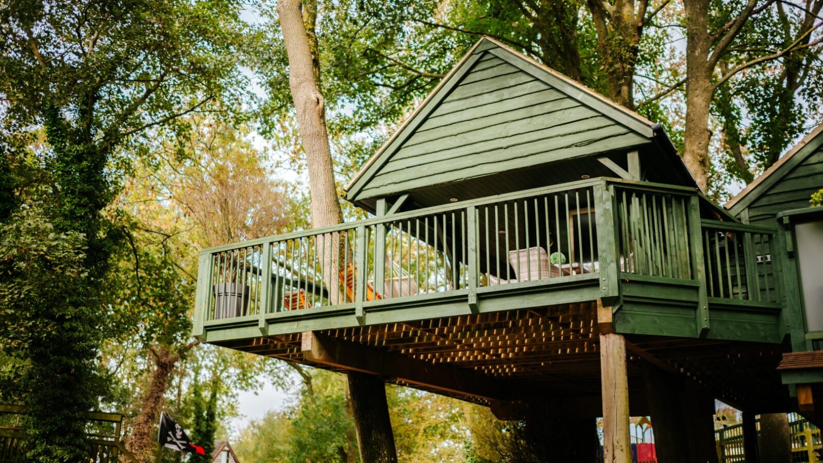 Wills Treehouse, a charming green retreat with a spacious balcony, is beautifully elevated among tall trees in a serene wooded area.