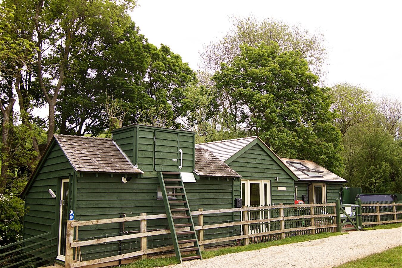 Jess’ Tree Bach is a charming nature retreat featuring green wooden cabins equipped with solar panels. Nestled among the trees, these delightful treehouses offer a perfect vacation rental spot, complete with a quaint gravel path leading to your tranquil escape.