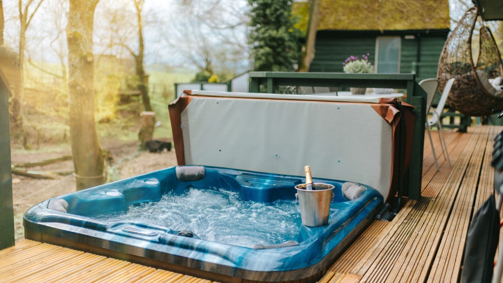 A charming lodge hosts an outdoor hot tub with bubbling water on a wooden deck, complete with a champagne bottle in an ice bucket, all nestled among the whispering trees.