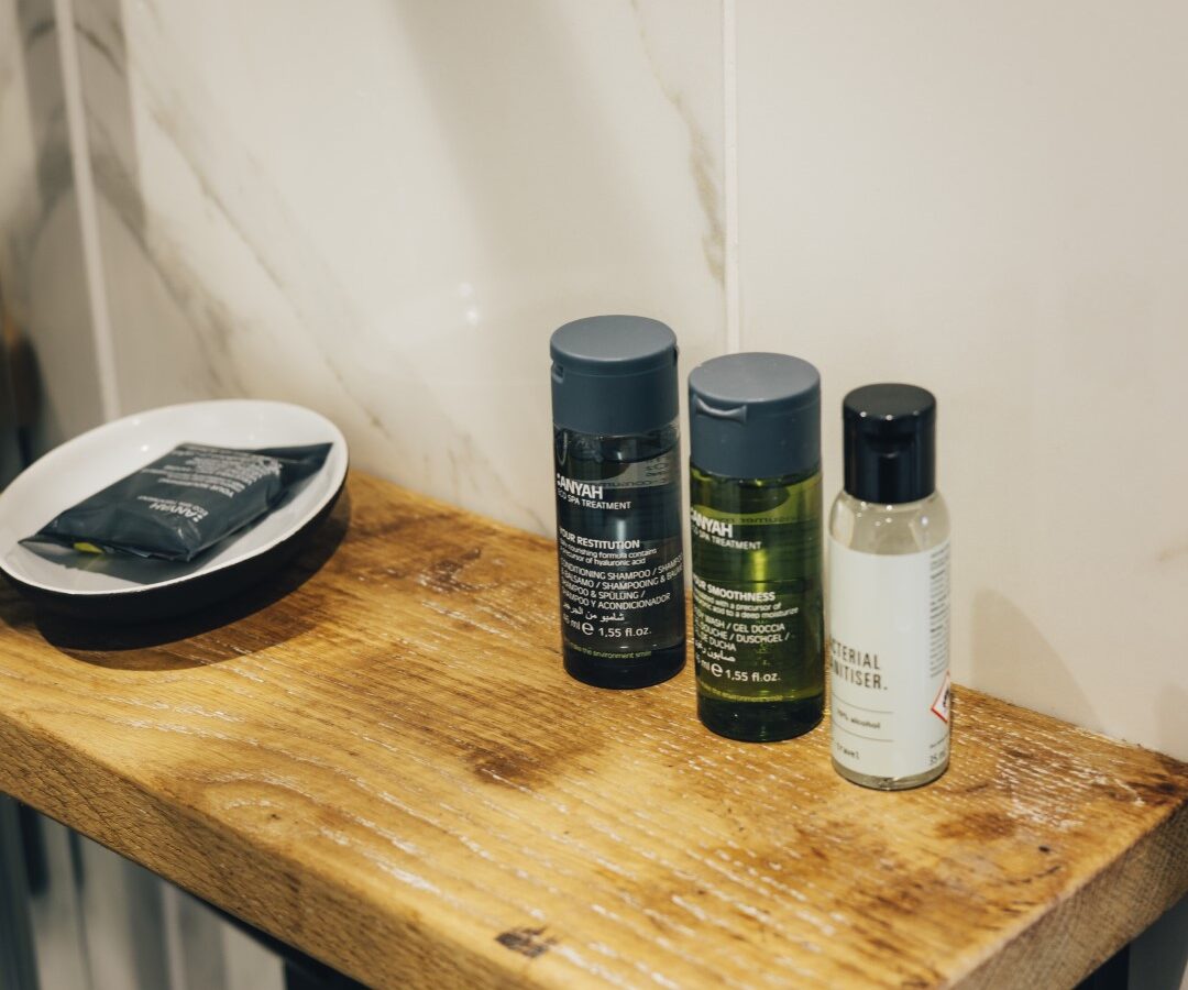 Nestled in the cozy Duck Pond Cabin, a small wooden shelf holds an array of essentials: shampoo, conditioner, body lotion bottles, and a soap dish.