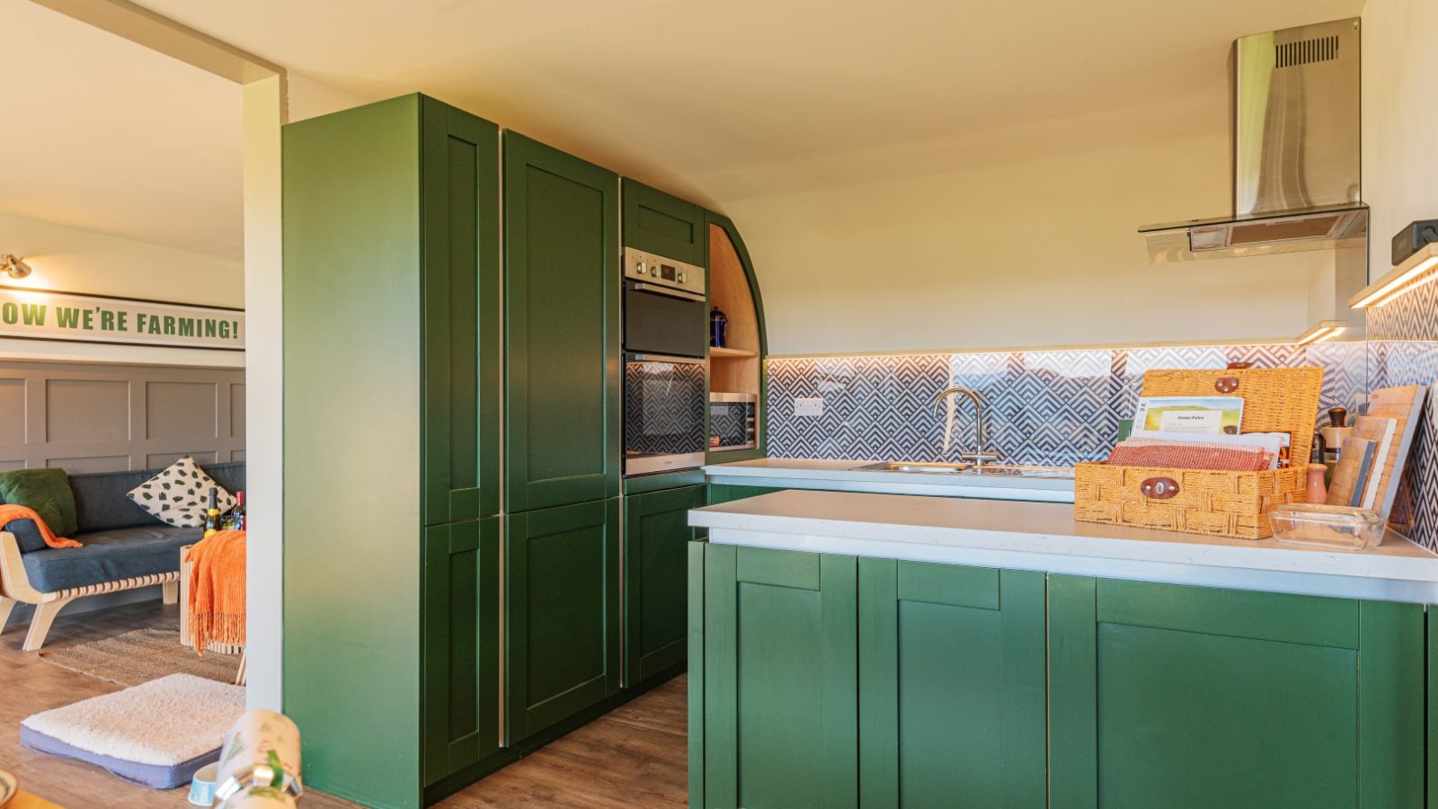 Pontypinna Hideaways offers a modern kitchen with green cabinets, an oven, a basket on the counter, and a patterned backsplash.