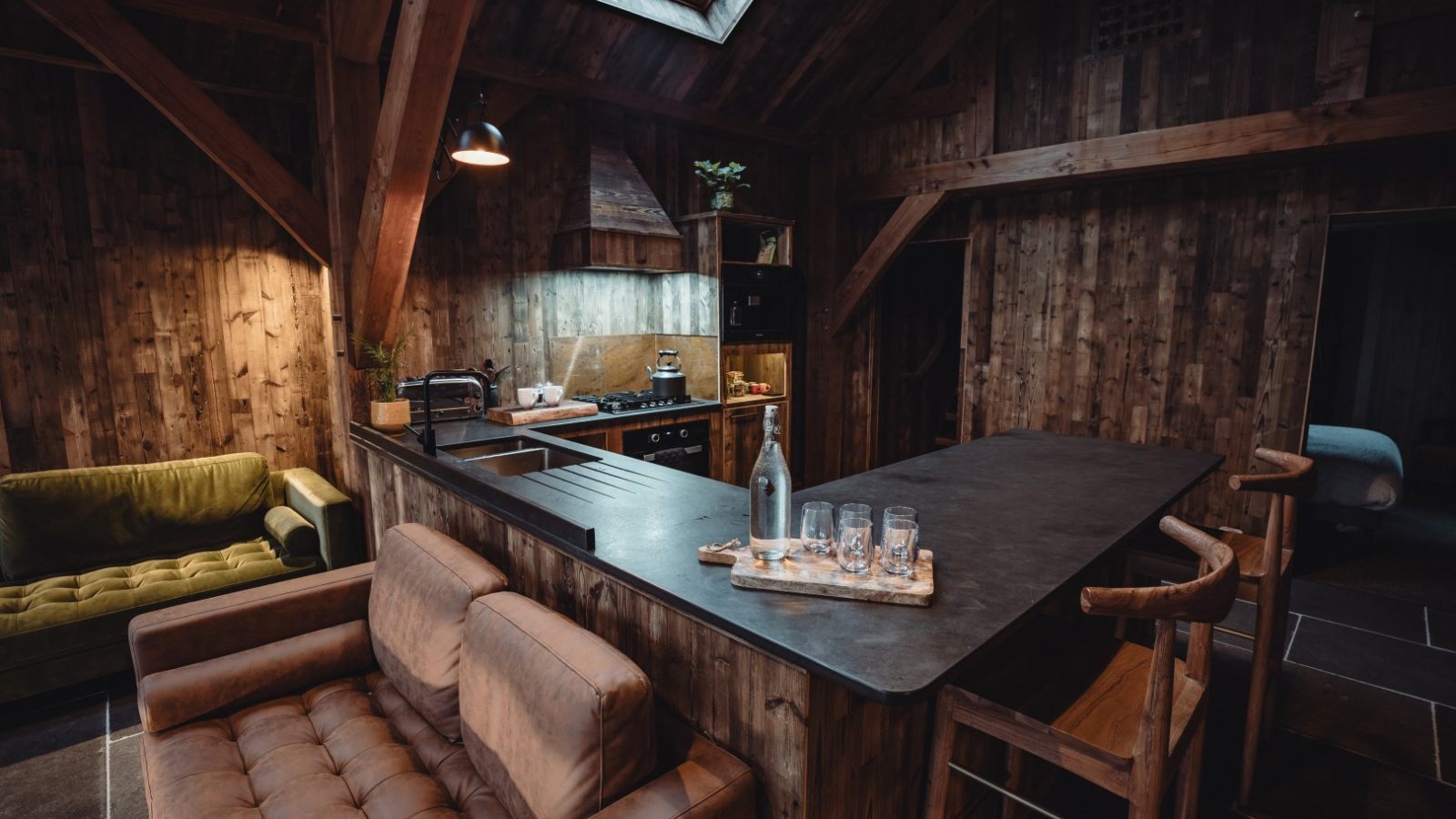 Cozy rustic kitchen with wooden beams, a central island, sofa seating, a skylight above, and views of the Orchard.