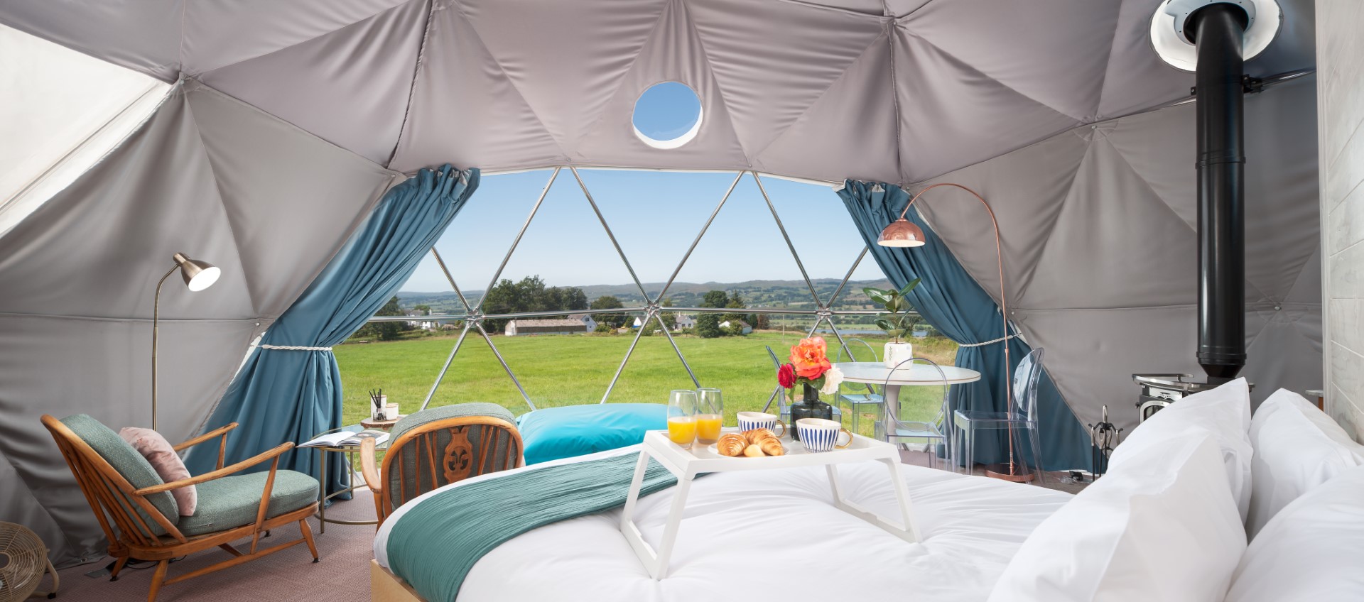 Experience the ultimate short break in Scotland within this cozy dome tent. Inside, you'll find a comfy bed, a delightful breakfast tray, and a seating area, all set against stunning views of the scenic countryside through a large window.