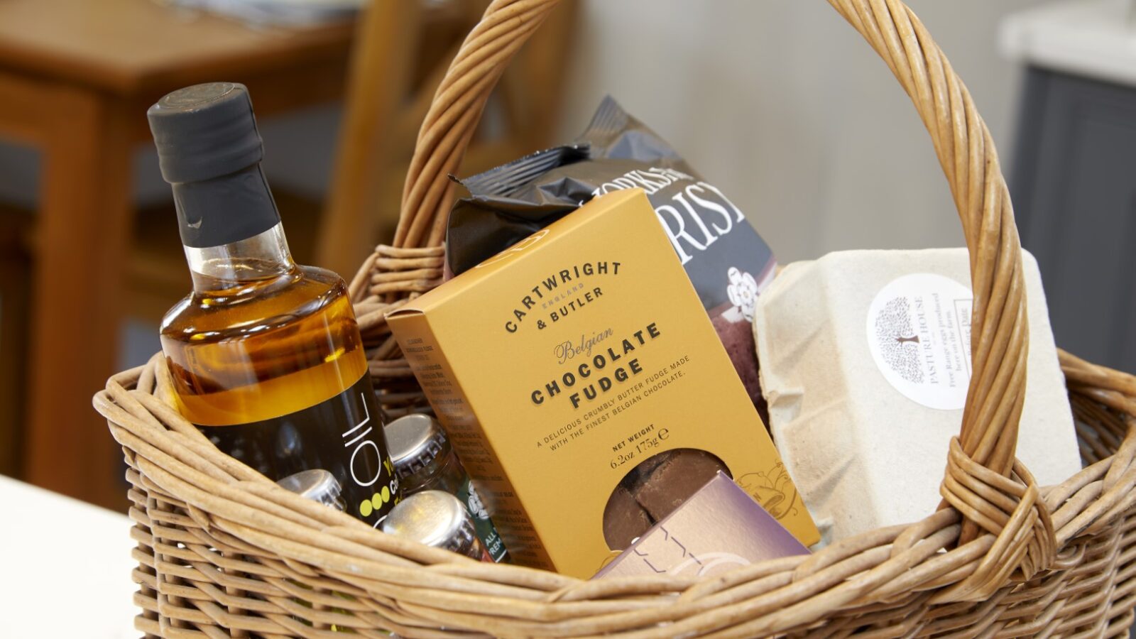 The Stables gift basket offers an exquisite selection of assorted items, featuring olive oil, chocolate fudge, crispy snacks, and artisanal soap.