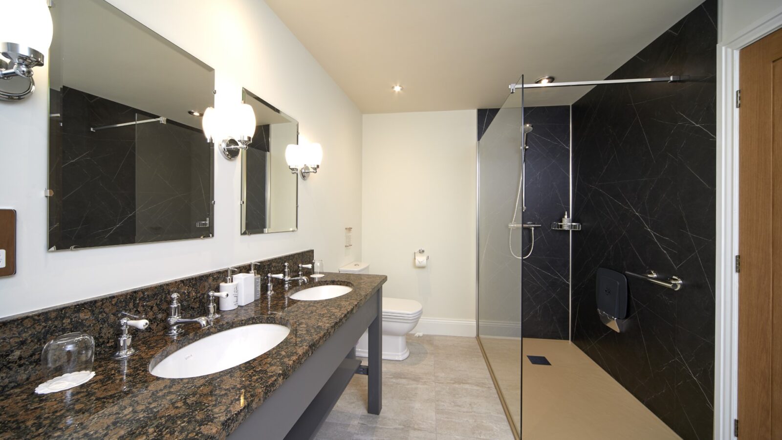 Modern bathroom with a double sink vanity, large mirrors, black accent wall, and glass-enclosed walk-in shower, designed to offer the tranquility of equestrian stables with earthy tones that mimic the serene feel of horse riding trails.