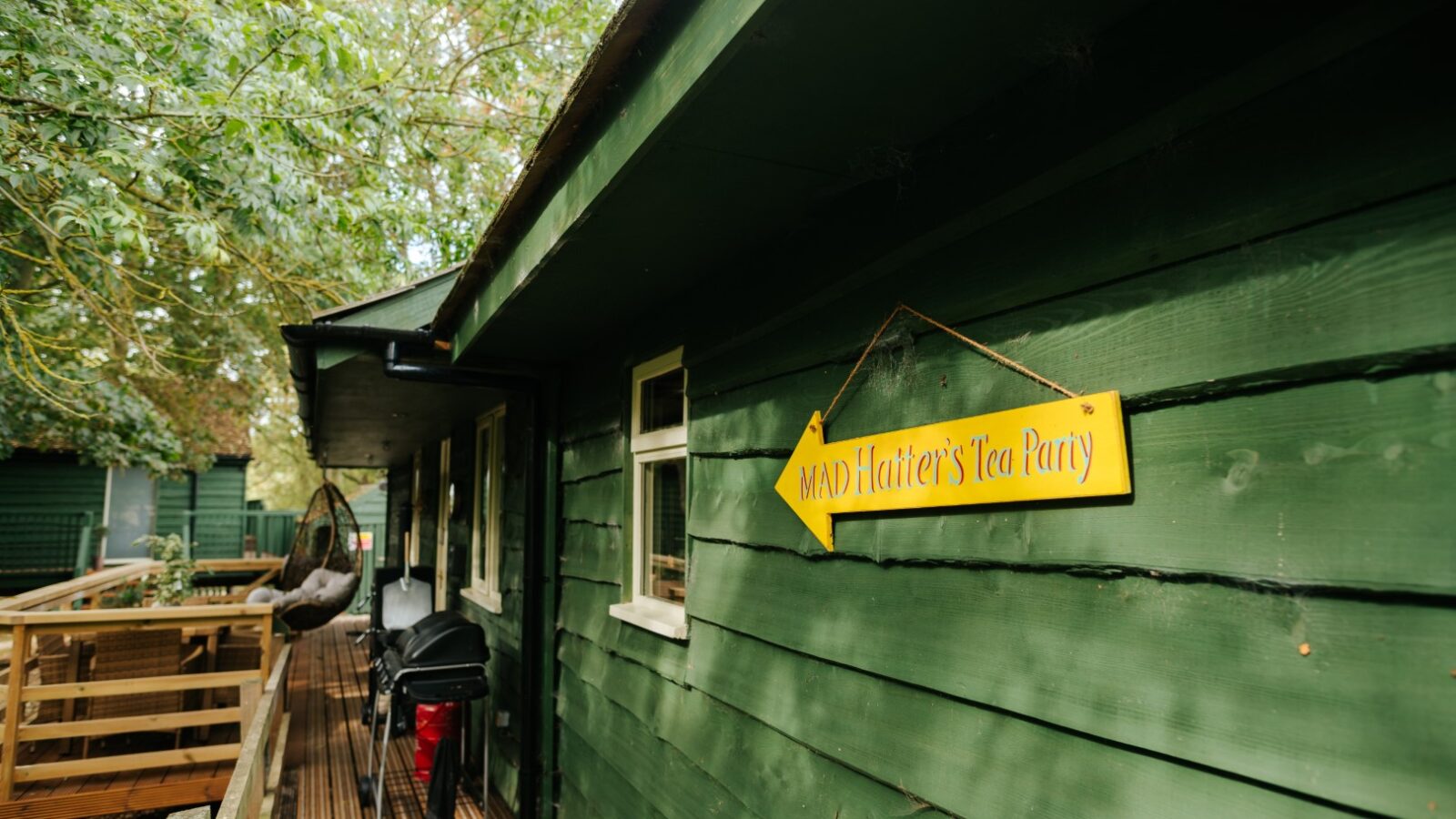 A green wooden house with a yellow sign reading 