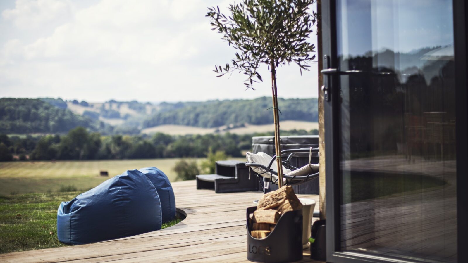 The Pontypinna deck features a blue bean bag, a potted tree, and offers scenic views of hills and fields—an ideal hideaway for relaxation.