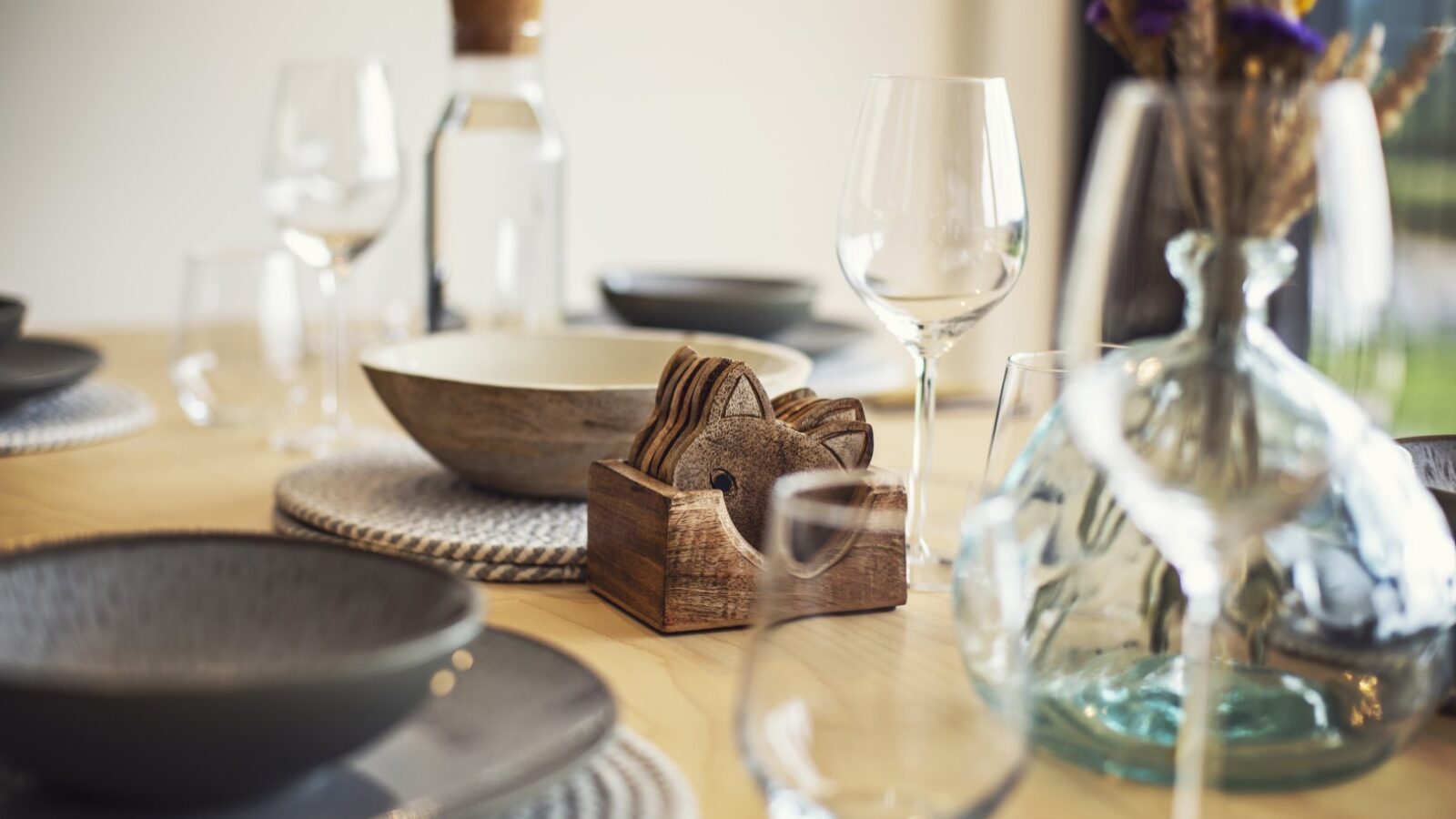 The table is elegantly set with glassware, ceramic dishes, and a wooden napkin holder, featuring a vase of purple flowers on the side—creating a perfect Pontypinna hideaway for intimate gatherings.