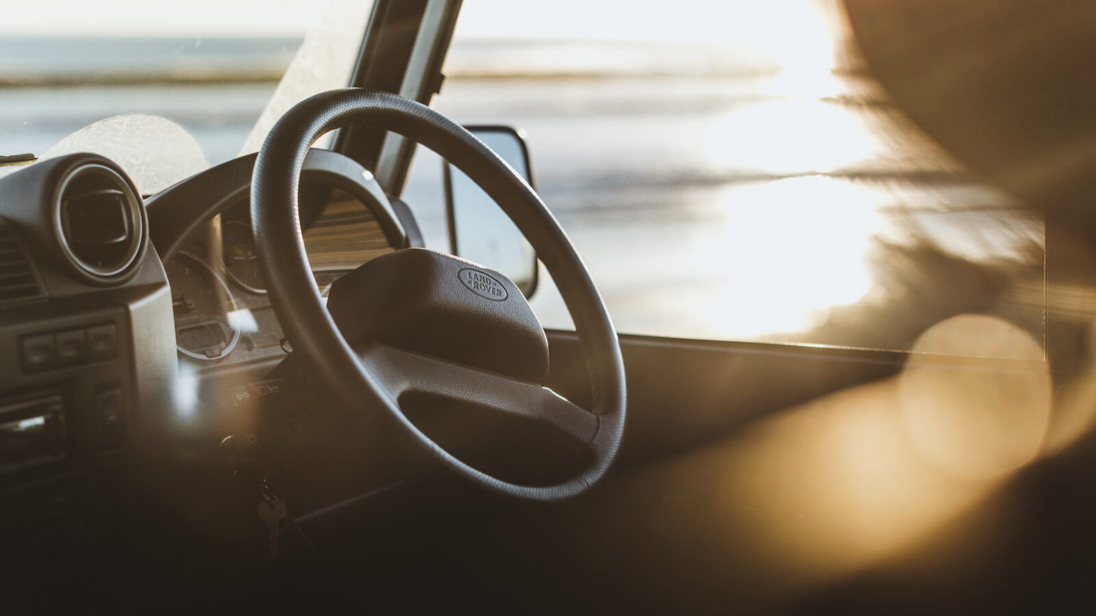 Sunlight streams through the window, casting a warm glow on the Defender's interior, highlighting its steering wheel and dashboard. Imagine planning your next camping adventure from this serene spot inside.