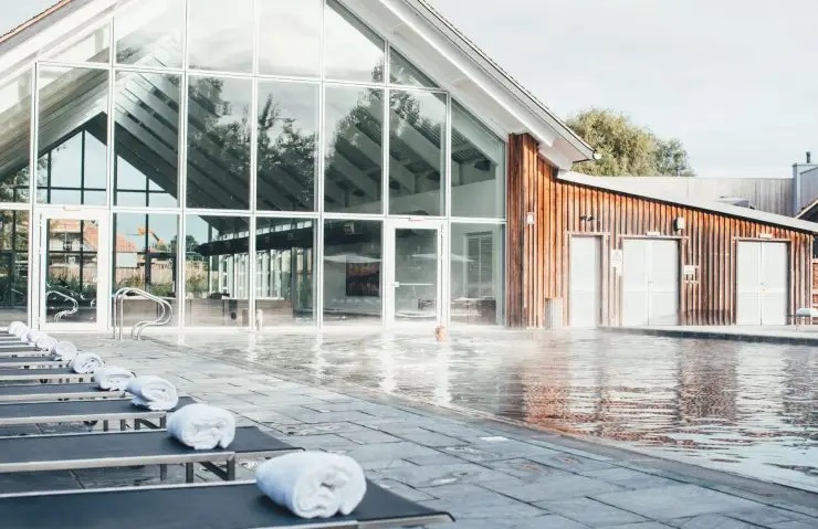 Modern building with large windows on Lamplight Island, next to an outdoor pool surrounded by lounge chairs with rolled towels.