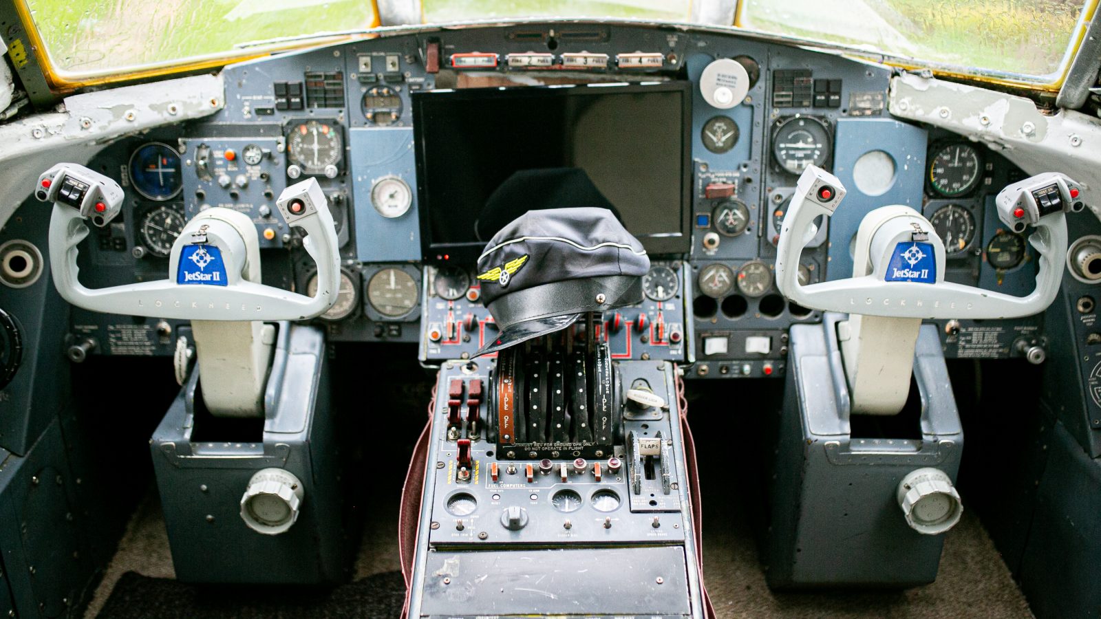 Cockpit of an airplane featuring numerous buttons, switches, and gauges. Two control yokes prominently display 