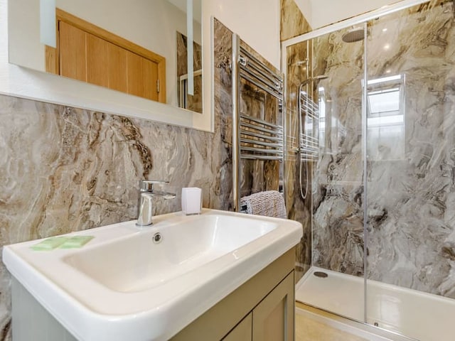 A modern bathroom features a sleek white sink with a rectangular basin and metal faucet. Above the sink is a large mirror. The walls have a marble-like pattern reminiscent of Penshenkin style. To the right, there is a glass-enclosed shower with a chrome showerhead. A heated towel rail is visible.