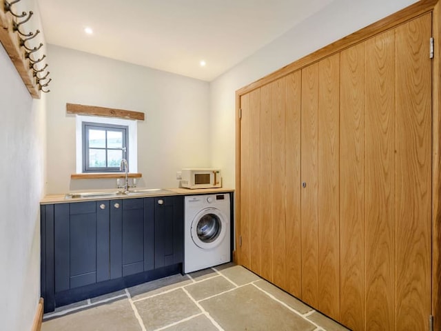 A laundry room reminiscent of a Penshenkin barn, featuring a wooden door on the right, a washing machine under a countertop in the middle, and a small window above the sink on the left. A row of hooks is mounted near the ceiling on one wall, and the floor is tiled with large square stones.