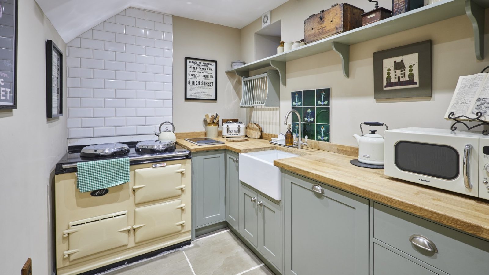 A retro kitchen at Gablebach, Black Mountain Escapes, features a cream stove, farmhouse sink, and green cabinets.