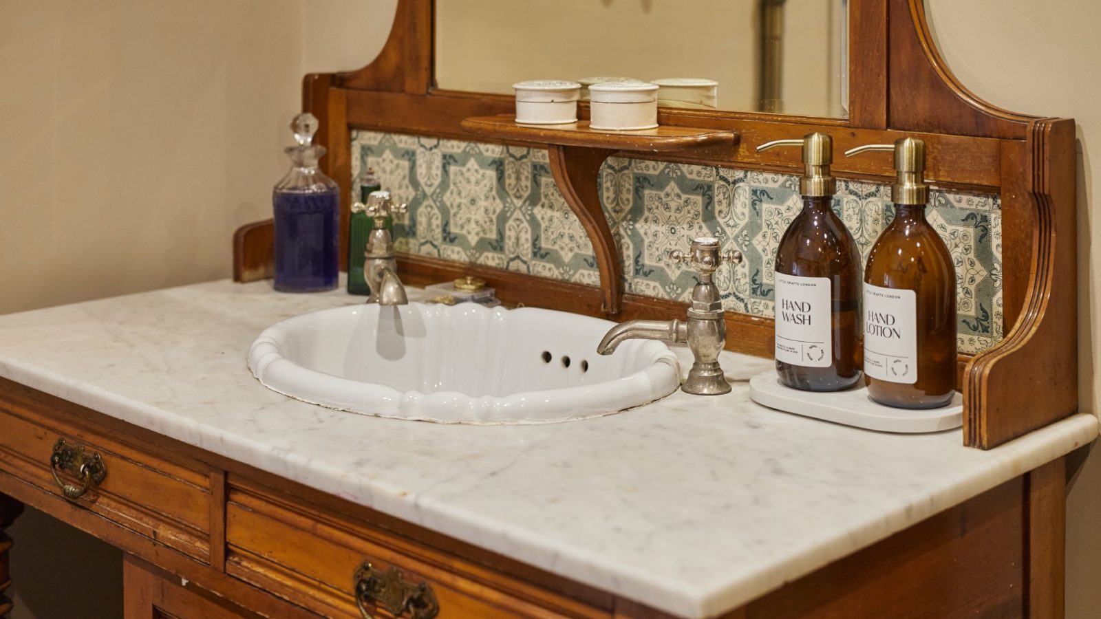 Antique bathroom at Gablebach, Black Mountain Escapes, features a wooden vanity, marble countertop, and ornate mirror.