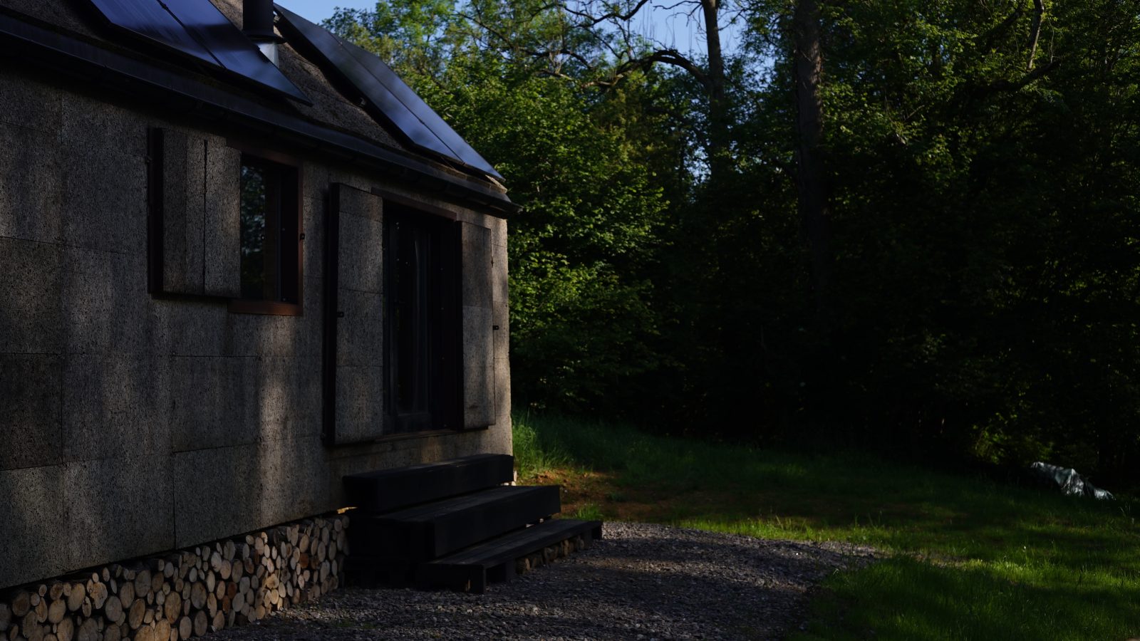 A quaint Korkhouse with solar panels on the roof, nestled among lush green trees. Wooden steps lead to the entrance, while a stack of logs rests beneath the structure. The scene is dappled with sunlight filtering through the trees.