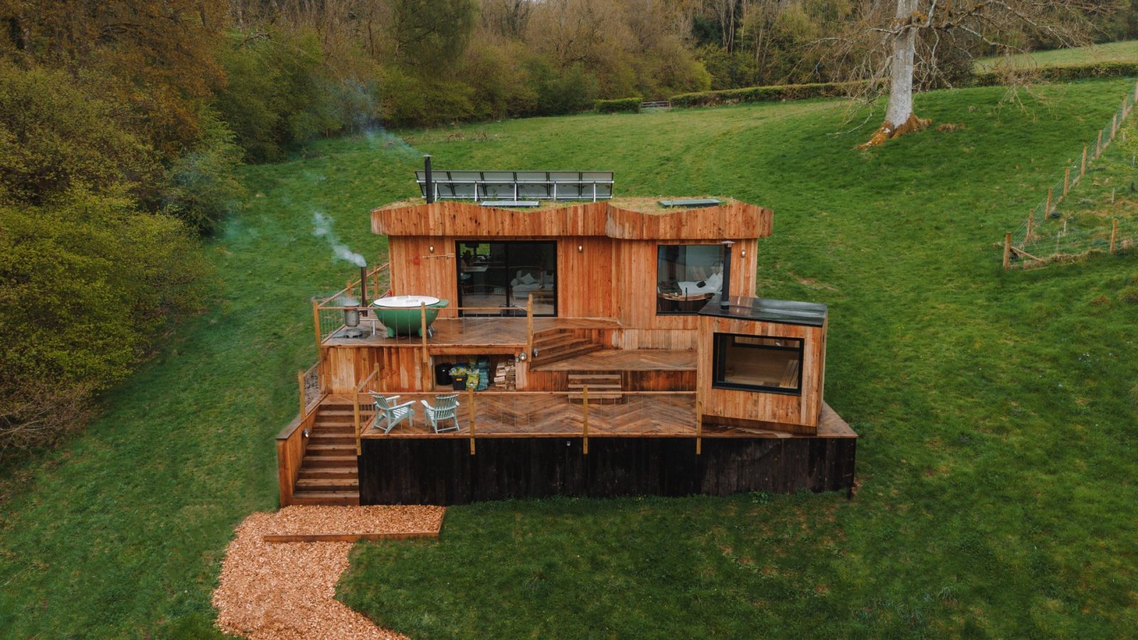 Nestled on a grassy hillside surrounded by trees, The Fold is a Scandi cabin with a deck, hot tub, and solar panels.