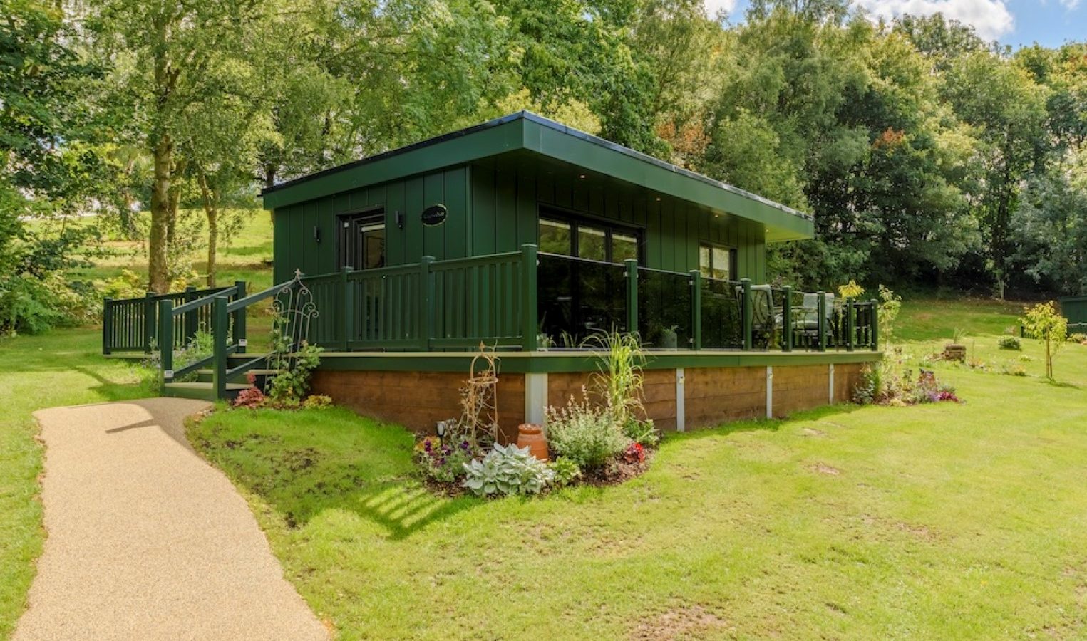 Rowley Meadow cabin nestled among lush trees, with a path to its entrance under a clear sky.