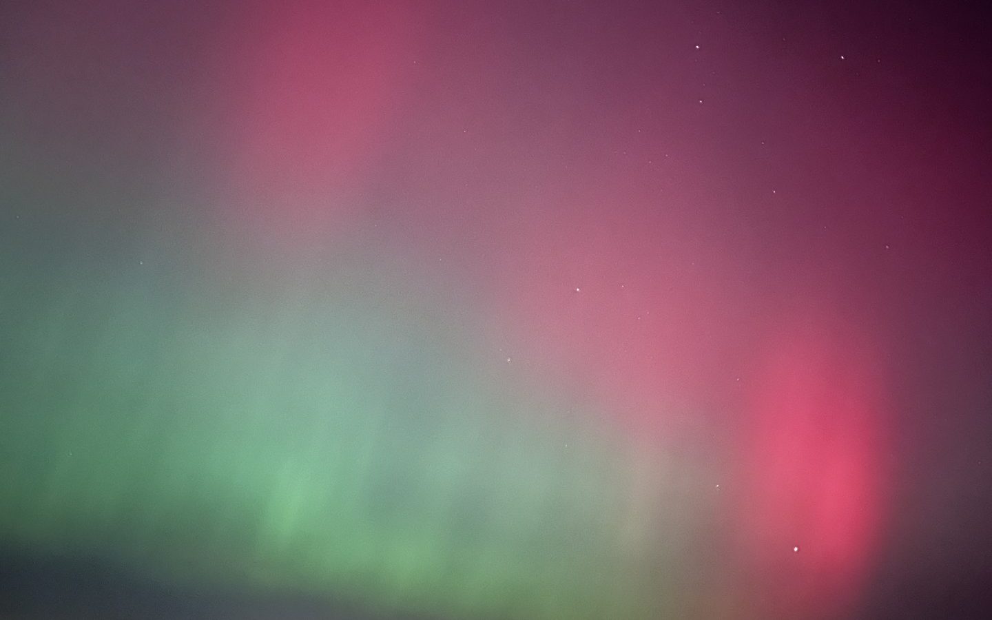 The sky above Breaks Fold Farm displays vibrant green and pink auroras, with stars scattered across the dark horizon.