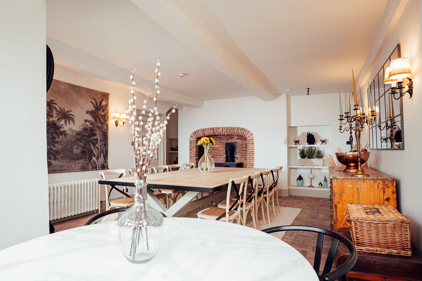 A spacious dining room for February Half Term Breaks, featuring a long wooden table, chairs, fireplace, and elegant wall art.