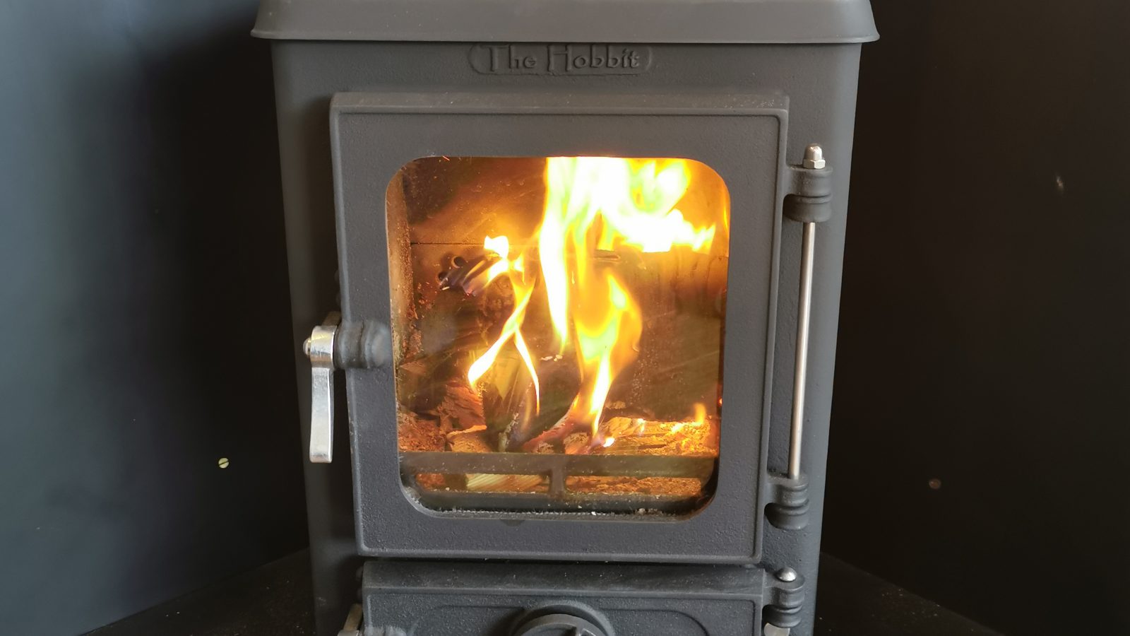 A black wood-burning stove in a romantic shepherds hut for couples, with a visible fire inside, emitting a warm glow.