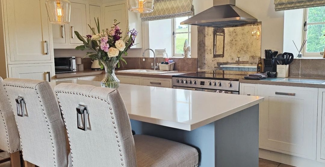 Modern kitchen in The Water Mill with a central island, upholstered chairs, flowers, and stainless steel appliances.