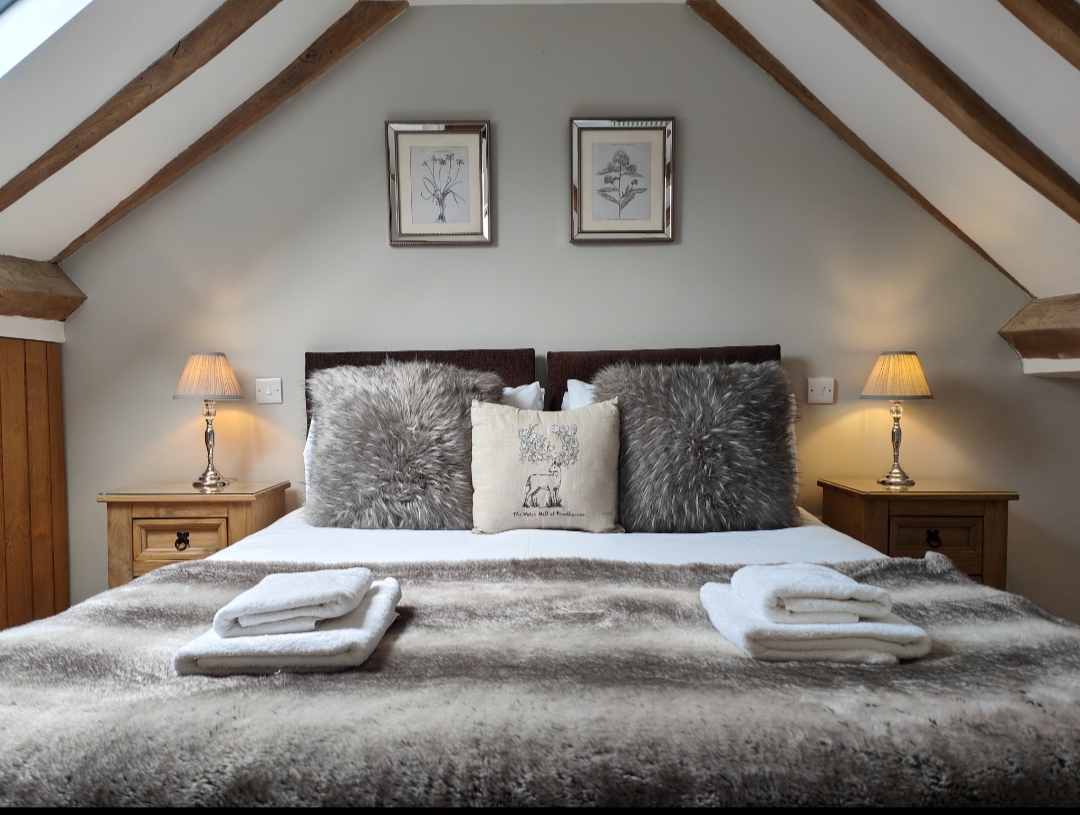 Cozy bedroom near The Water Mill, with a large bed, fluffy pillows, soft throw blanket, bedside lamps, and framed pictures.