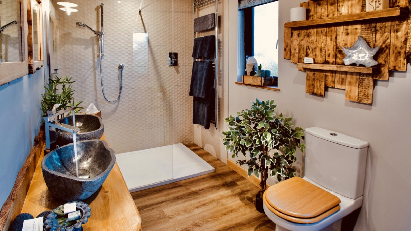 Treetop Hideaway: Bathroom with a walk-in shower, dual stone sinks, wooden accents, potted plant, and decorative shelving.