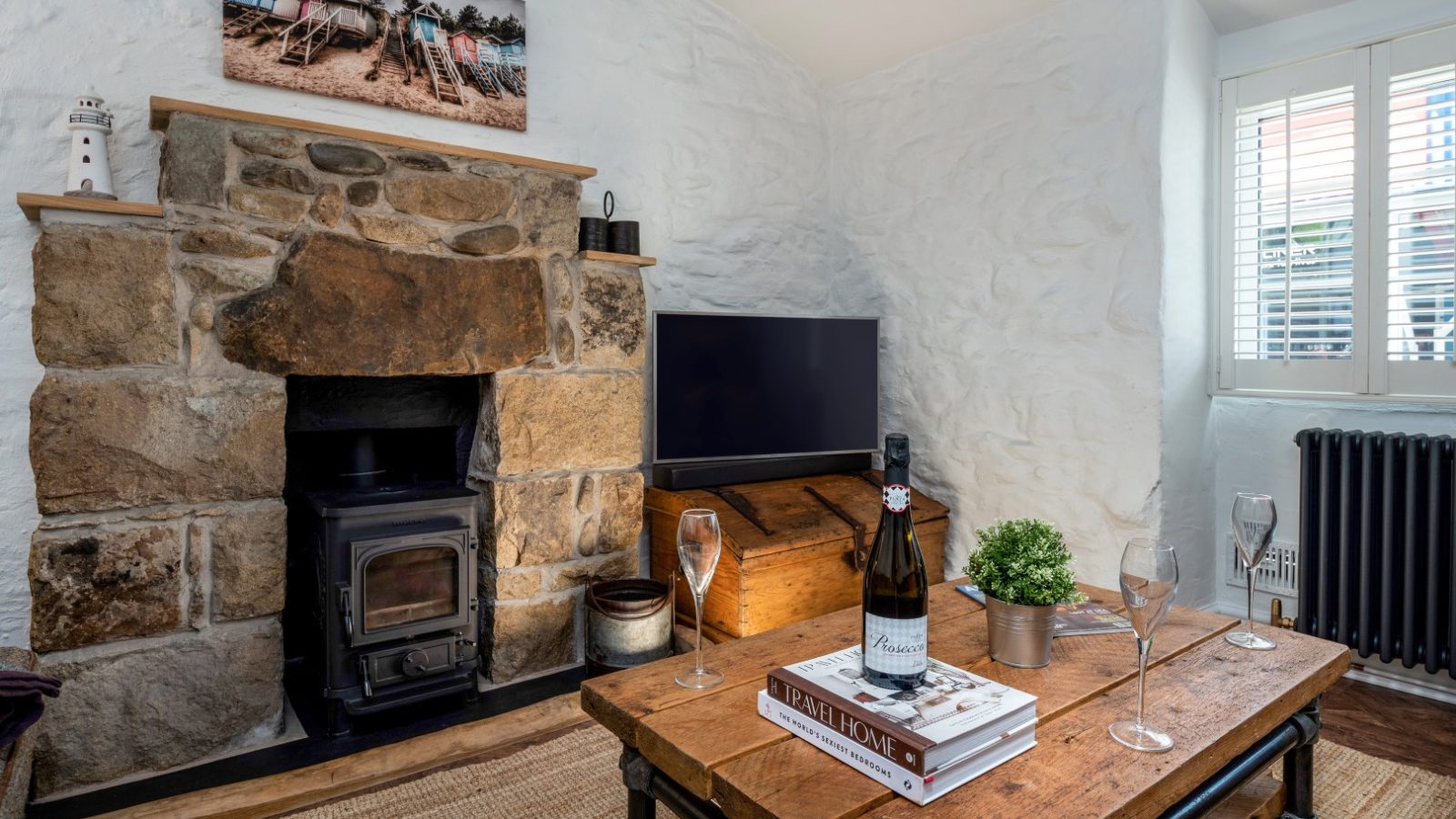 Cozy room with stone fireplace, TV, and wooden table. Wine sits beside 