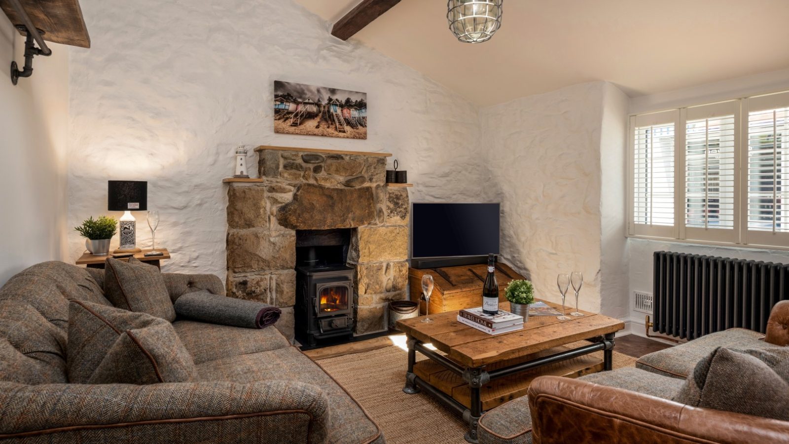 Cozy living room with stone fireplace, sofas, wooden coffee table, and rustic decor, evoking an Arfor charm under a beamed ceiling.