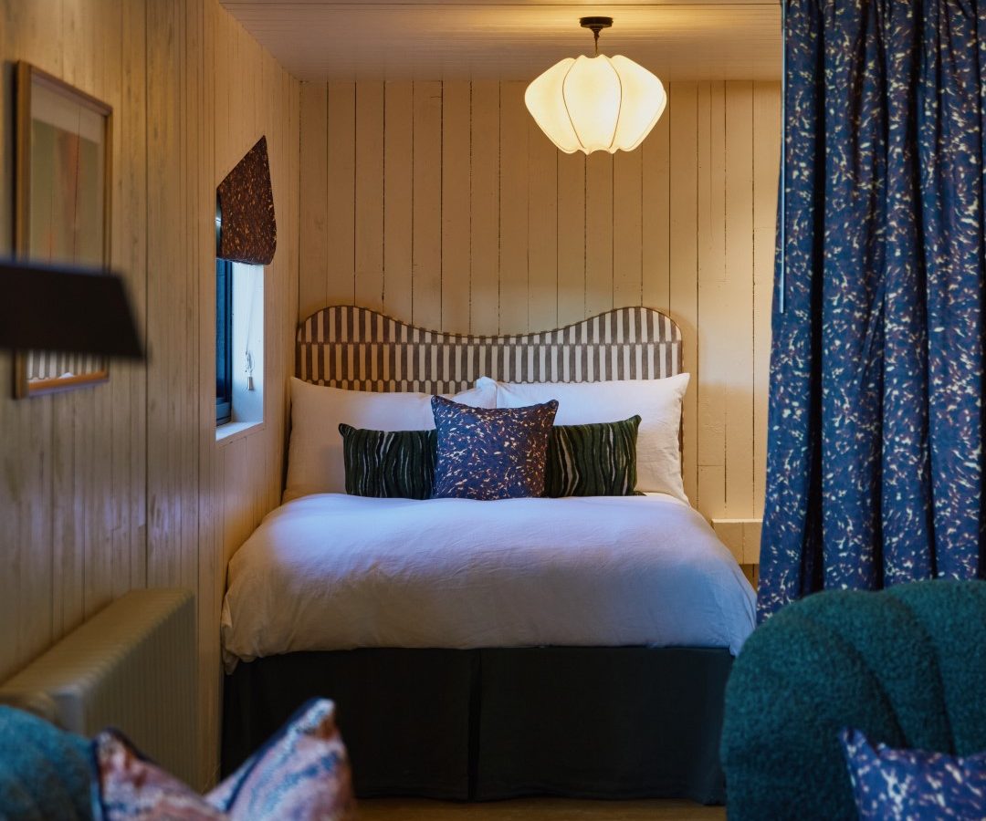 Bonington Farm's cozy bedroom features a double bed and pendant light, with green upholstered chairs in the foreground.