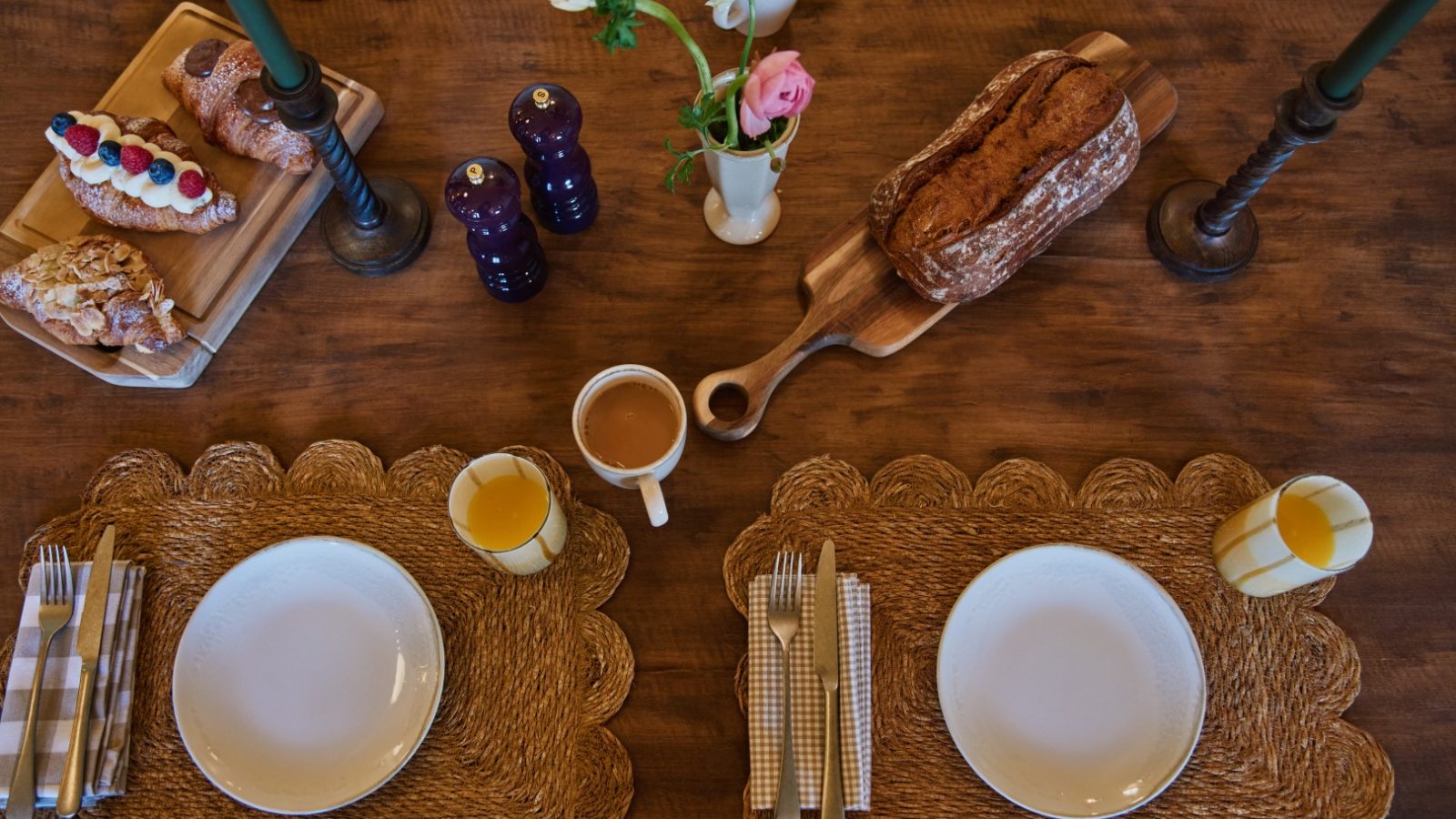 Table set for breakfast with Bonington Farm croissants, juice, coffee, and flowers in a vase.