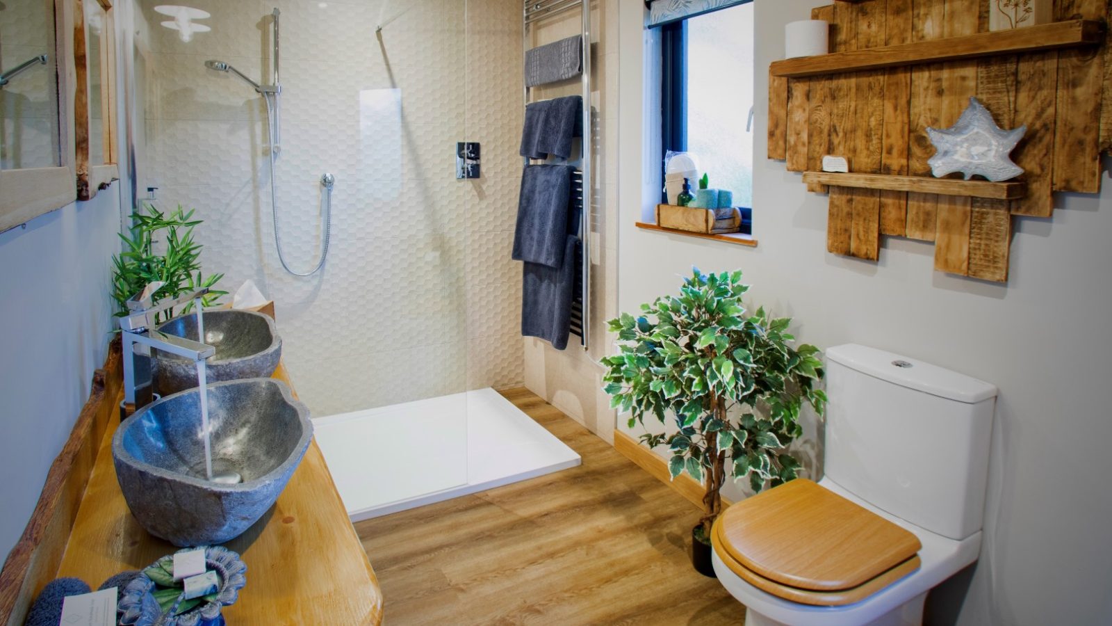 Modern bathroom in Treetop Hideaways with wooden accents, stone sinks, glass shower, toilet, and wall shelves for decor.