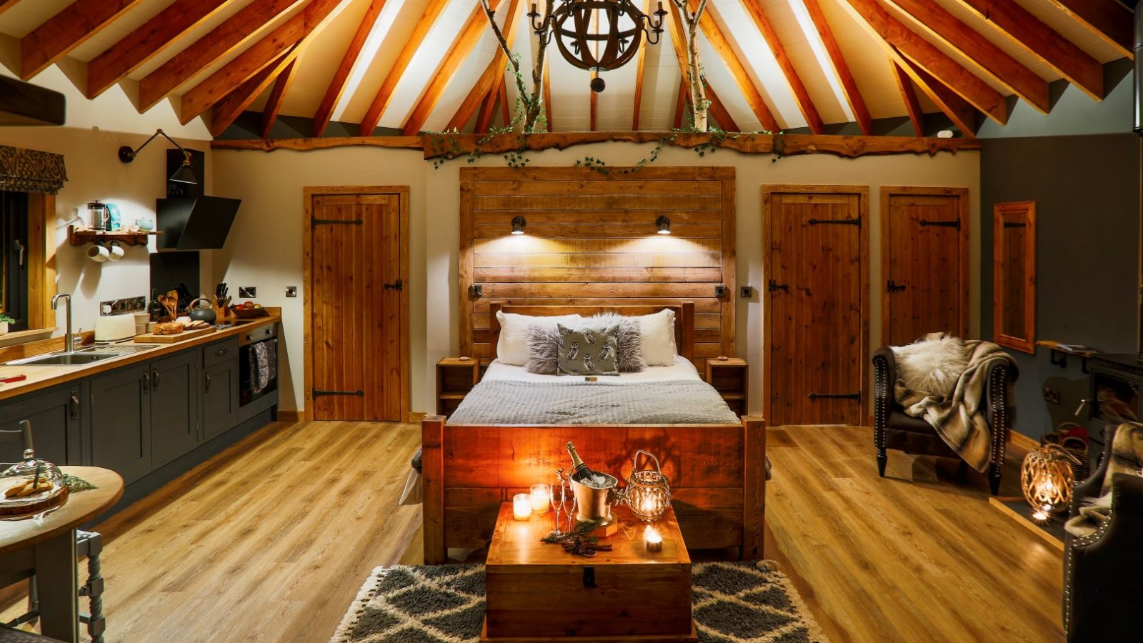 Cozy Treetop Hideaways interior with a wooden ceiling, bed, armchairs, and warm lighting creating an inviting atmosphere.