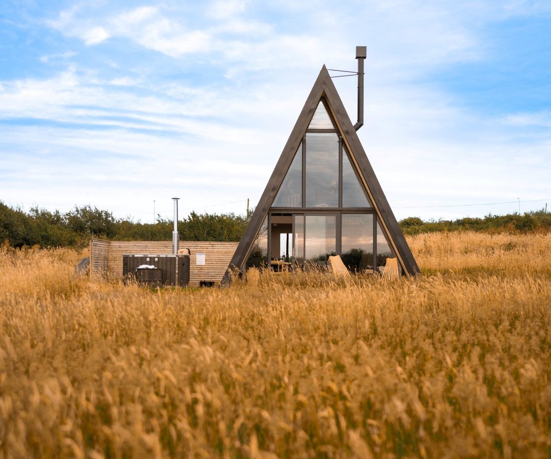 A-frame cabin with large glass windows at Wilder Retreats, perfect for nature getaways under a wide blue sky.