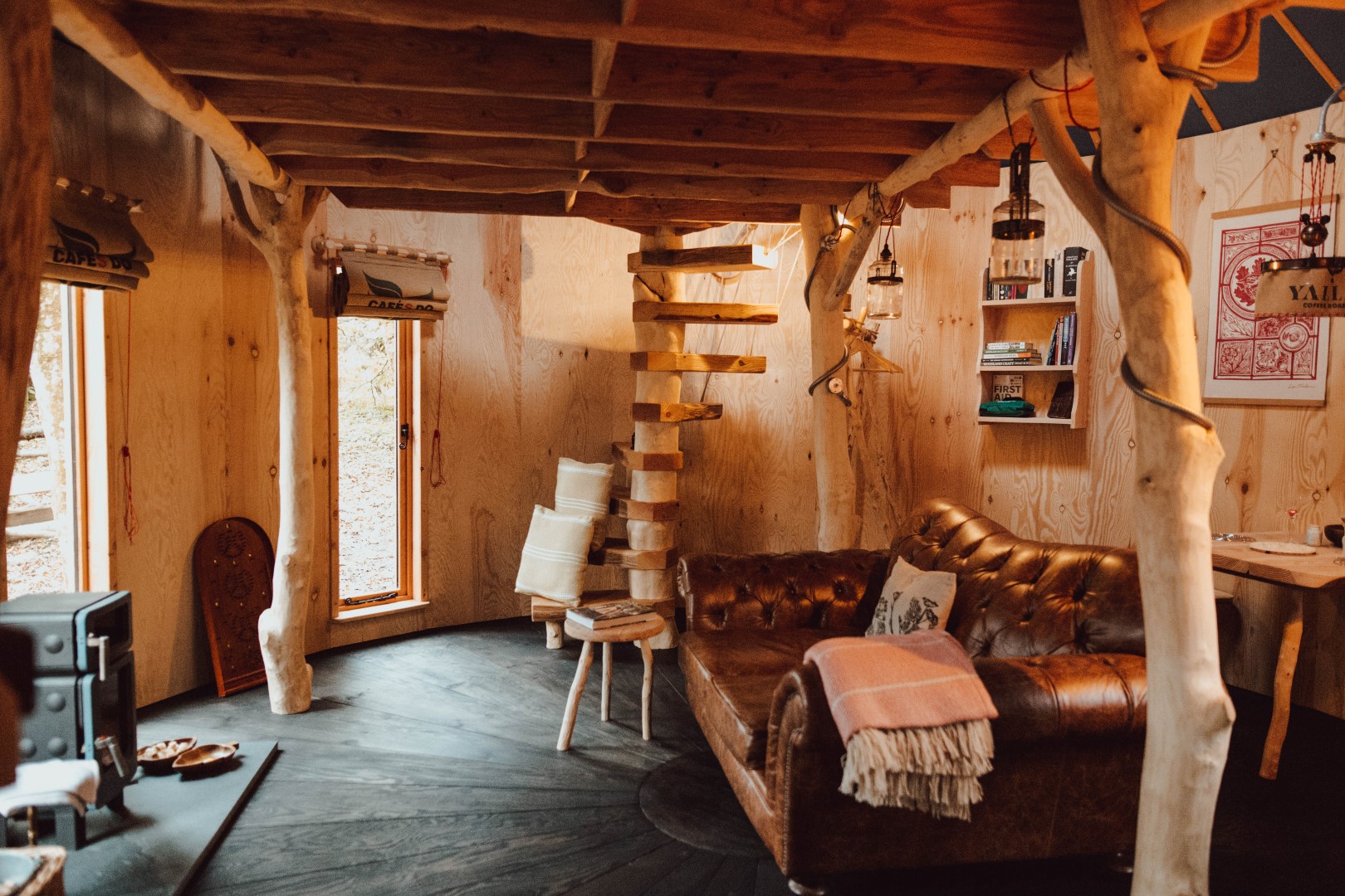 Rustic wooden interior with a spiral staircase and wood stove, perfect for a cosy romantic glamping getaway for two in Cornwall