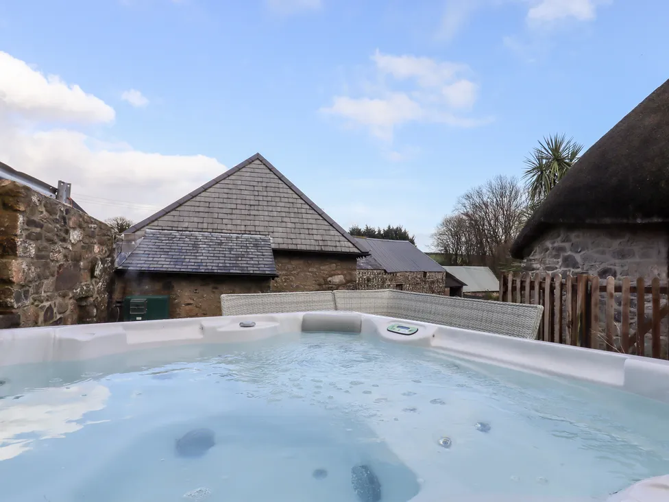 Outdoor hot tub with stone buildings and Bagtor Granary rooftops in the background on a clear day.