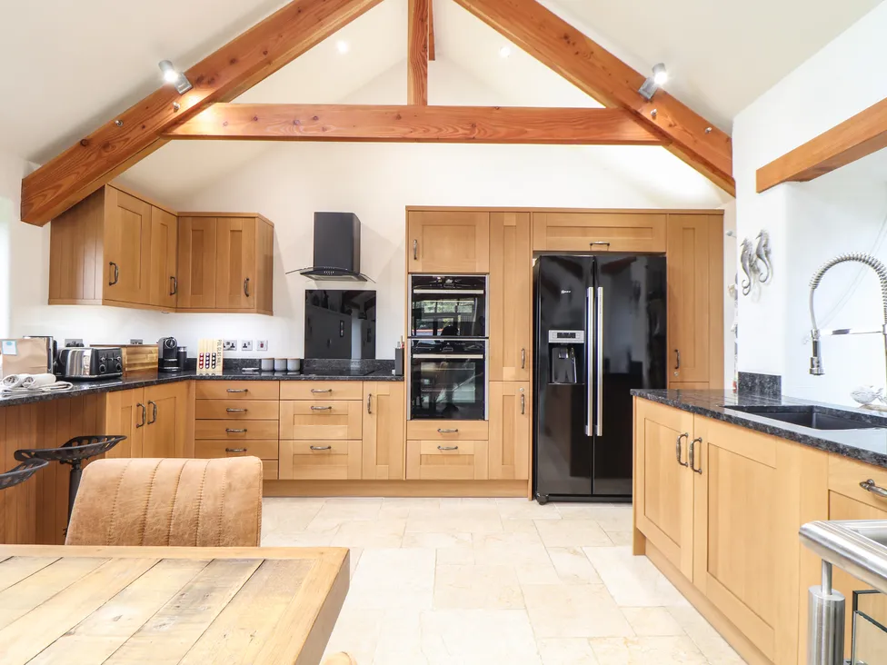 Modern kitchen with wooden cabinets, black appliances, and vaulted ceiling inspired by Pol Glas Hall's rustic charm.