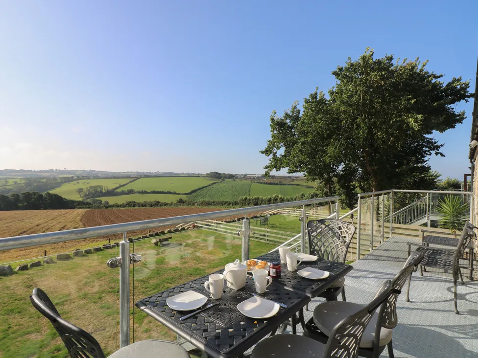Outdoor table set for breakfast on a balcony at Pol Glas Hall, overlooking green fields and rolling hills.