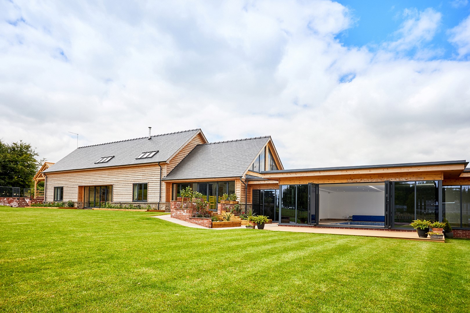 Modern house with large windows on a spacious lawn near The Barn at Pudleston Court, a charming wedding venue.