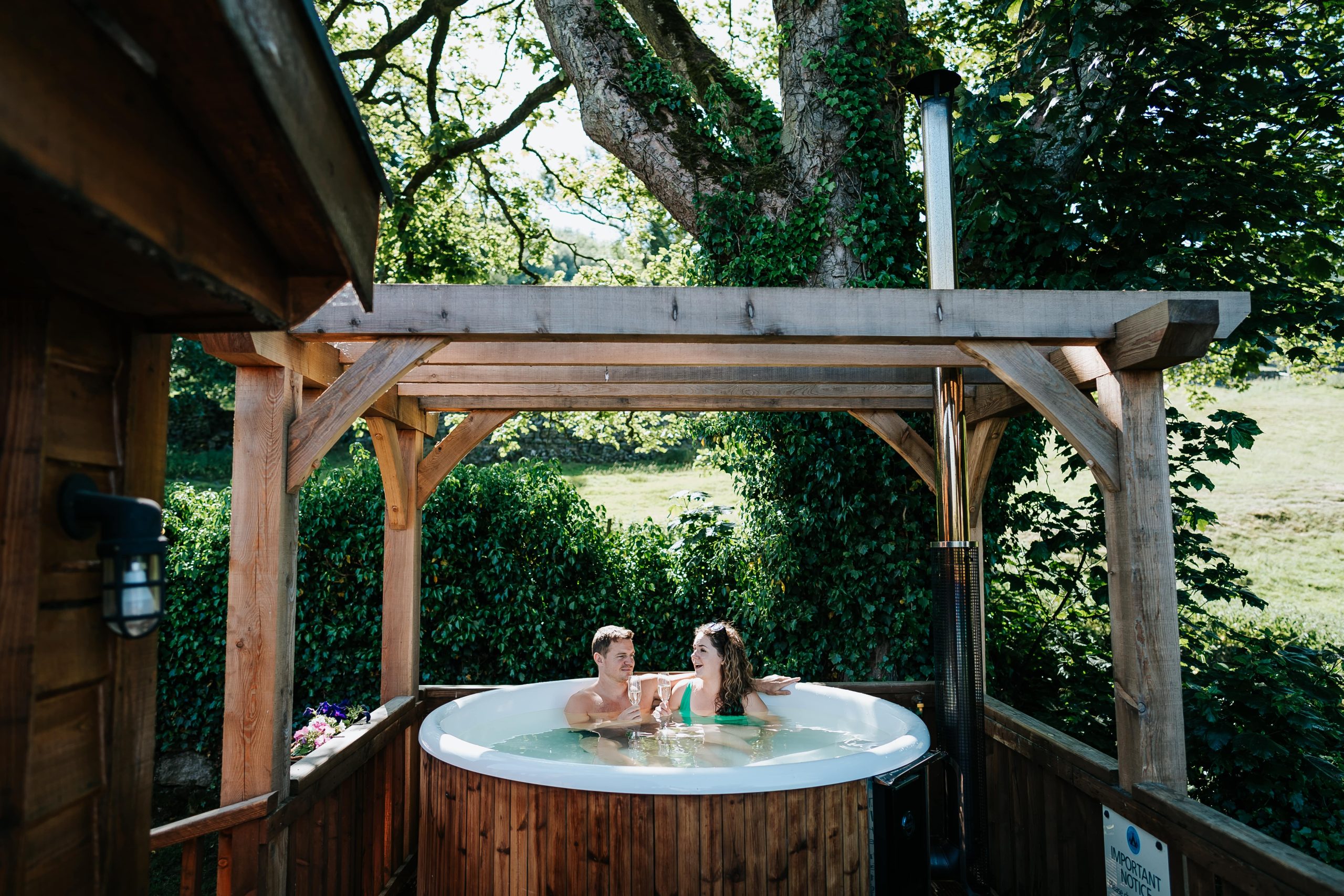 couple cheers with champagne glasses in a hot tub on a UK honeymoon at Howgill Lodge